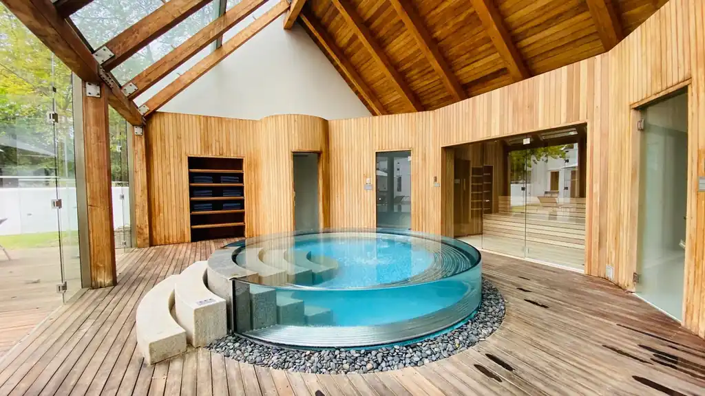 Moderne Wellness-Suite mit Holzarchitektur und kreisförmigem Jacuzzi.
